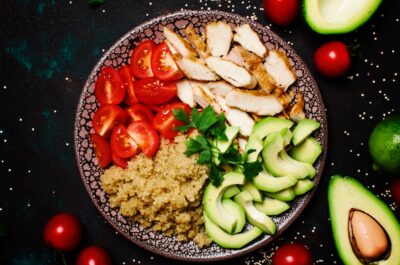 Healthy food, avocado, quinoa, chicken and tomatoes on plate, top view