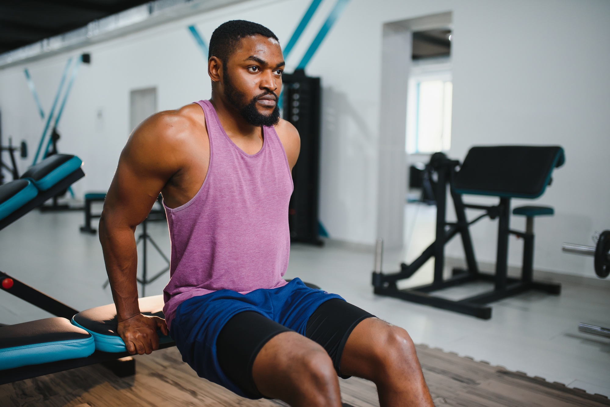 Weight training African doing bodybuilding in gym.